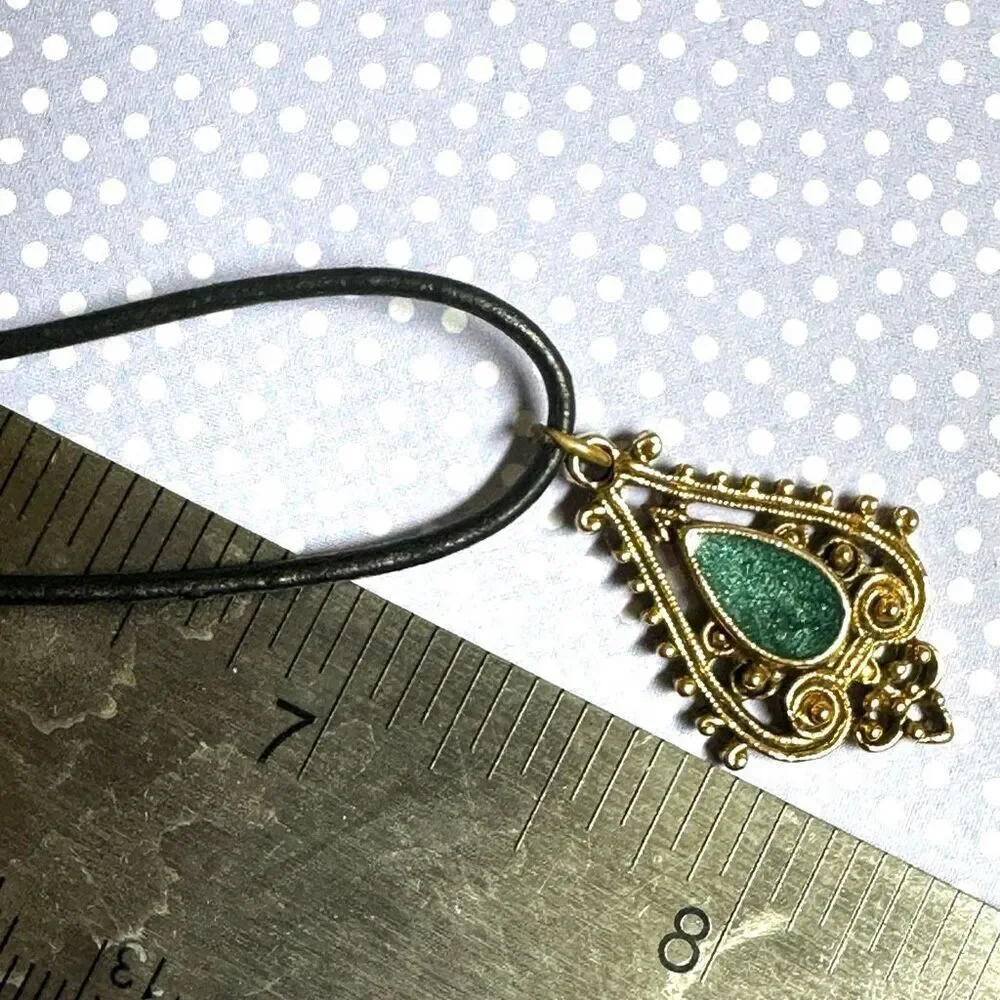 Green and gold tone pendant necklace on black cord